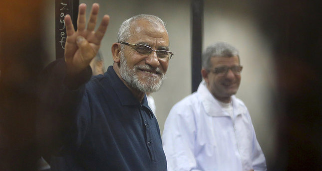 File photo of Muslim Brotherhood's Supreme Guide Mohamed Badie flashing the Rabaa sign at a court on the outskirts of Cairo